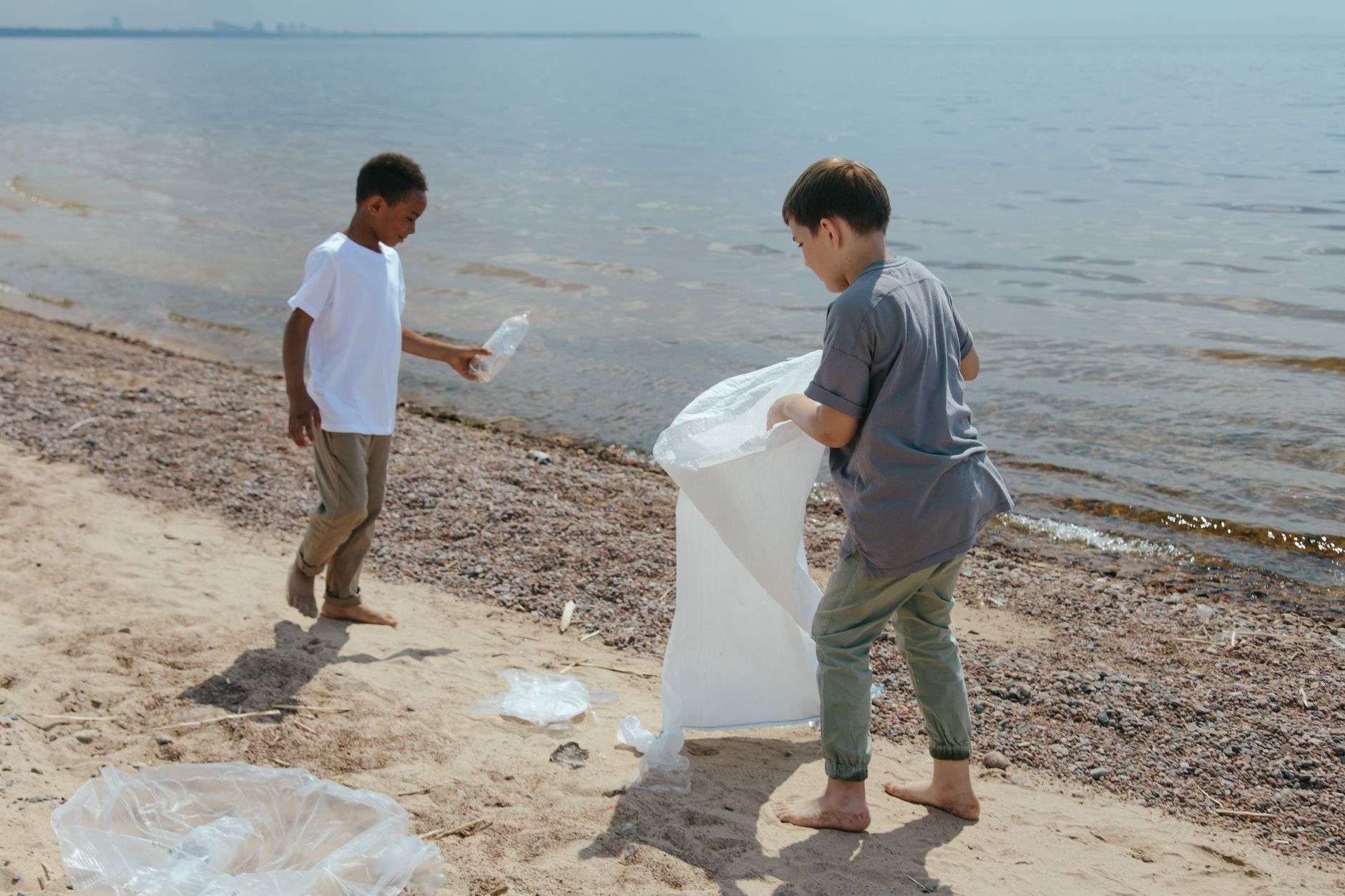 Volunteers collecting litter into trash bags along a shoreline
