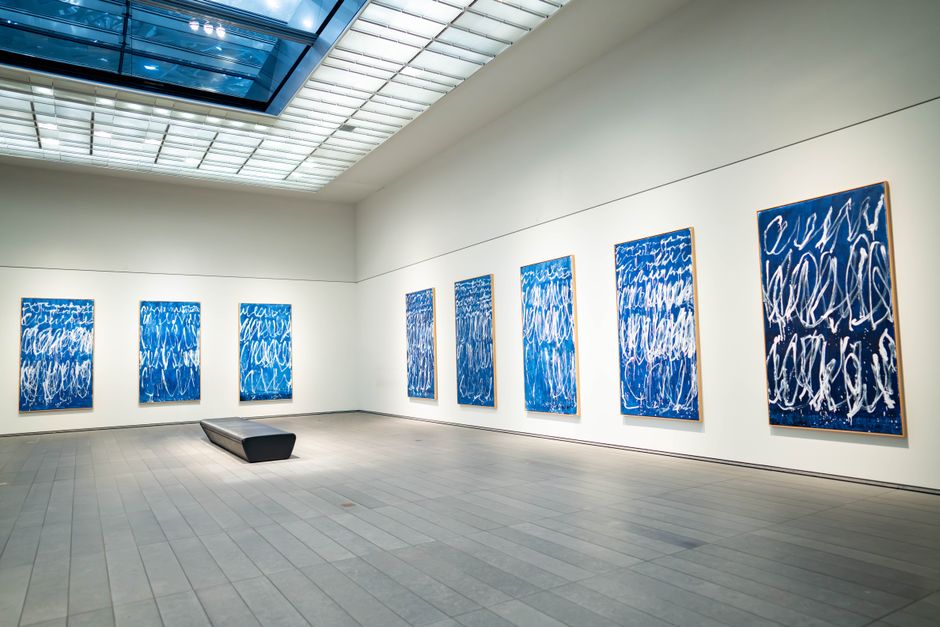 Framed paintings displayed on white gallery walls at an indoor art show