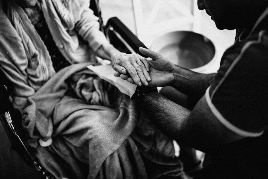 A caregiver gently holding the hand of a person receiving care