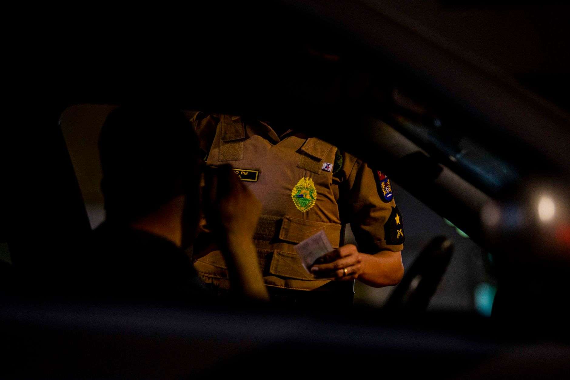 Police vehicle with flashing lights behind a car pulled over on a highway at night
