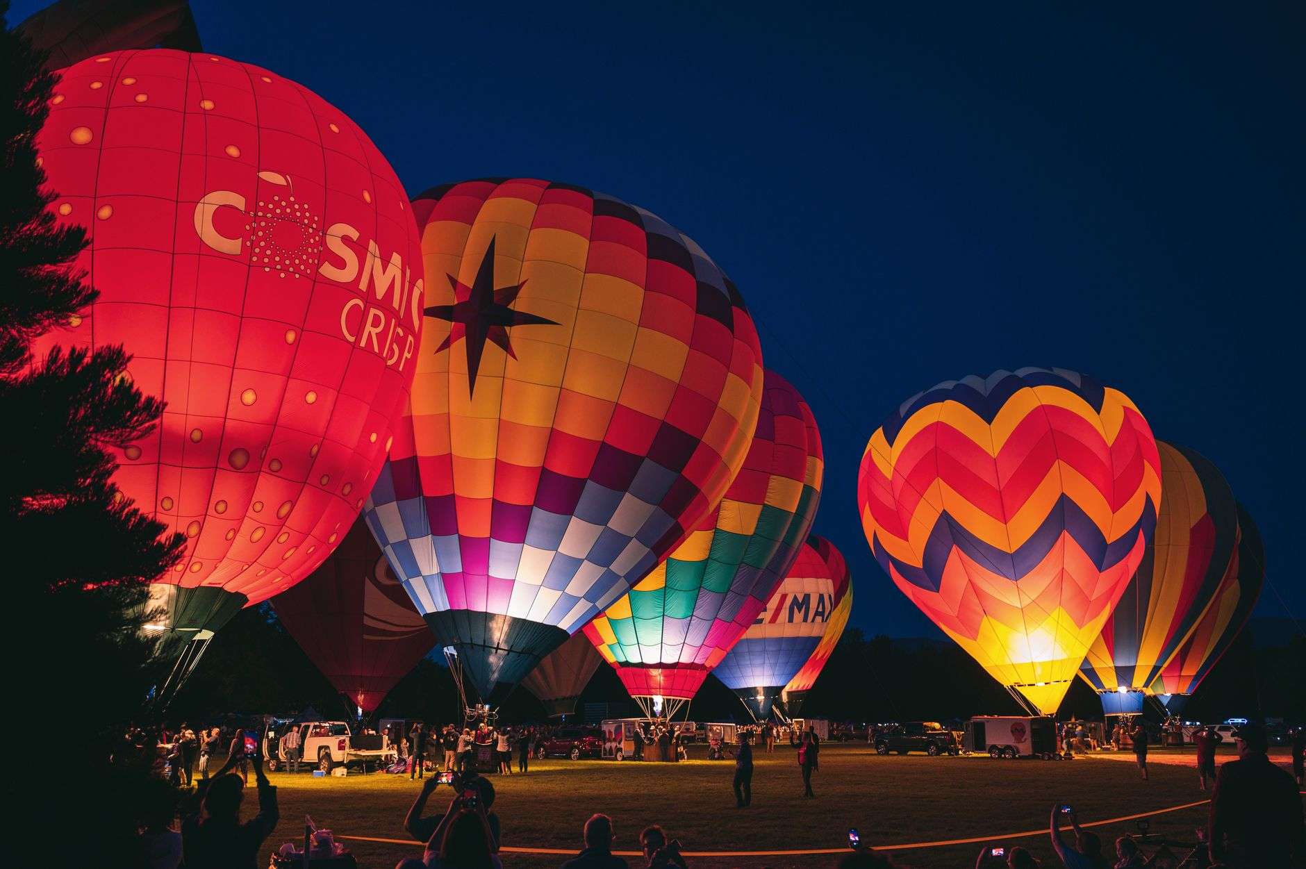 Tethered hot air balloons glow brightly against a darkening evening sky