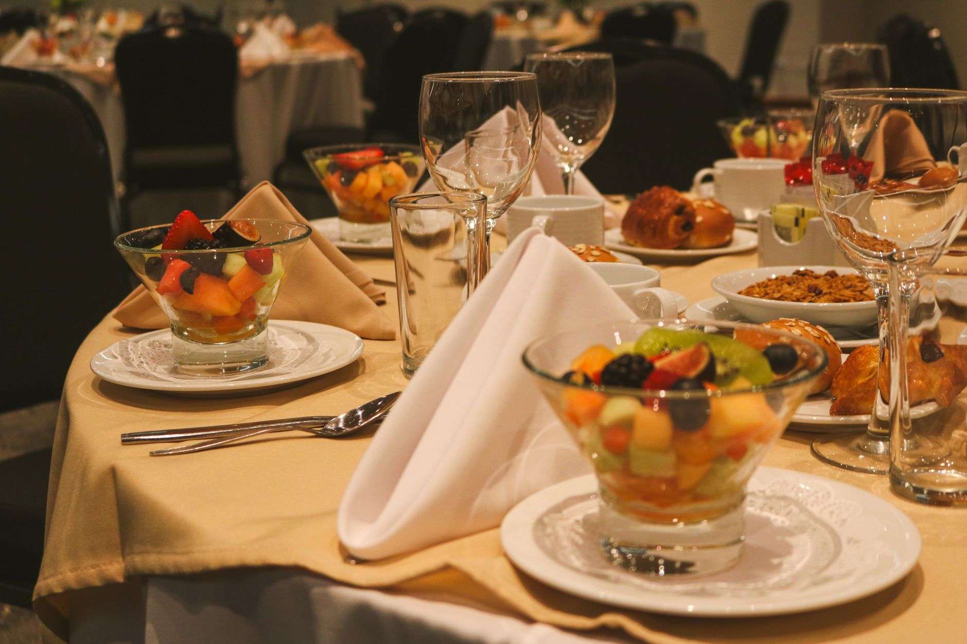 Table set for a breakfast banquet with fresh fruit, pastries and coffee cups