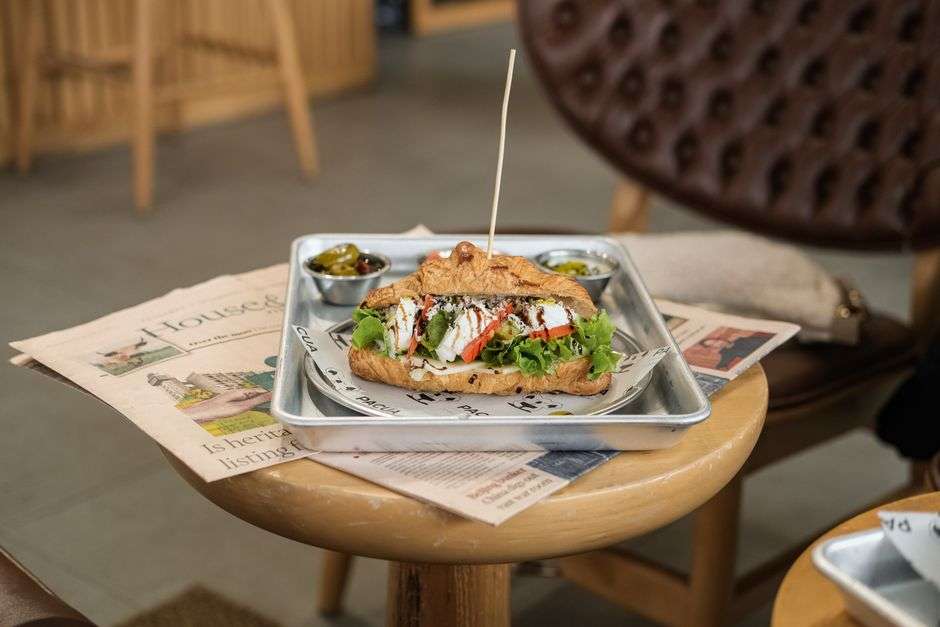 A bowl of homemade soup with a sandwich on a casual cafe table