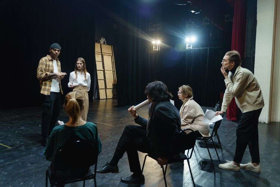 Actors performing live improvisational comedy on a small stage before an audience