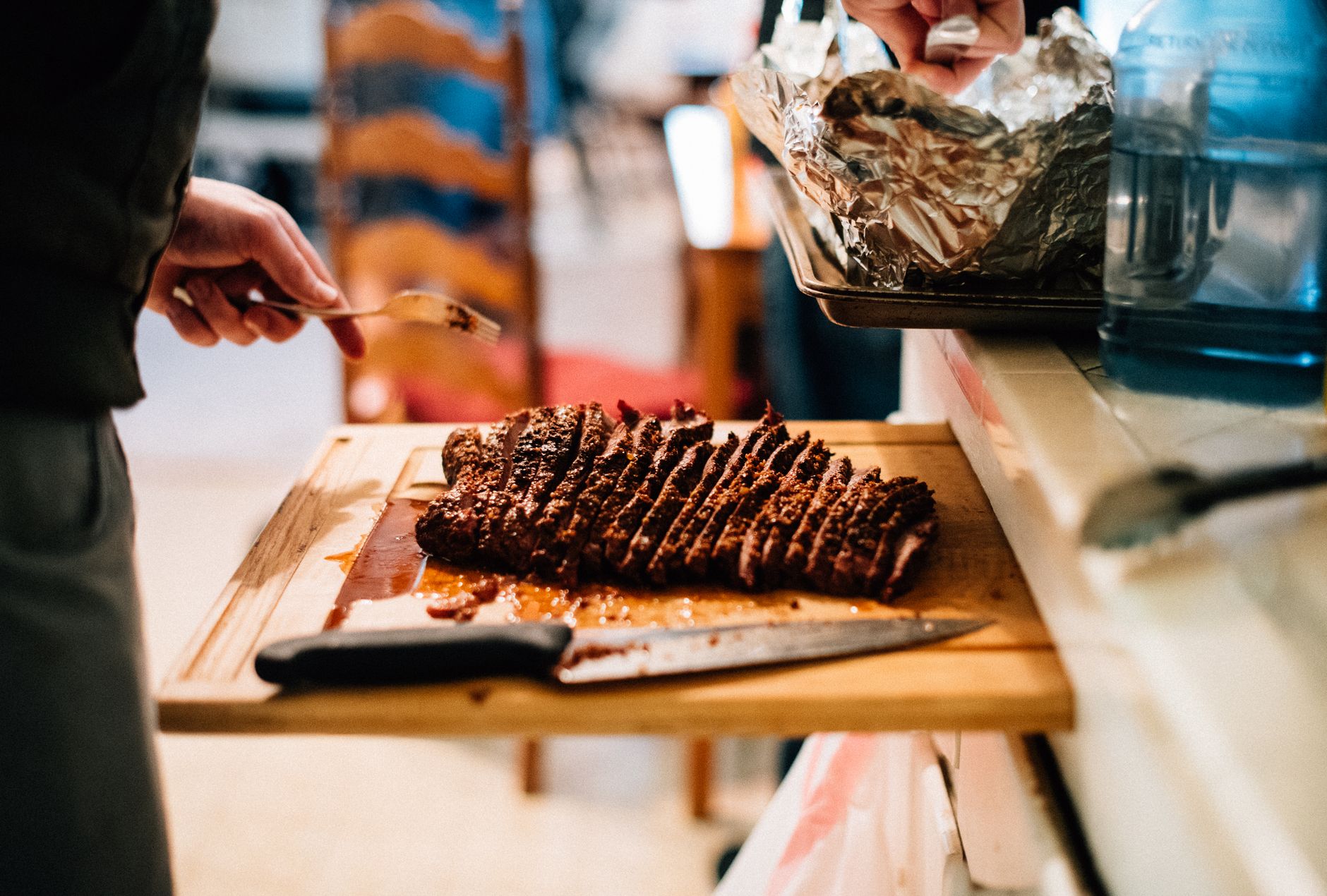 Sliced smoked brisket and ribs on a wooden board with barbecue sides