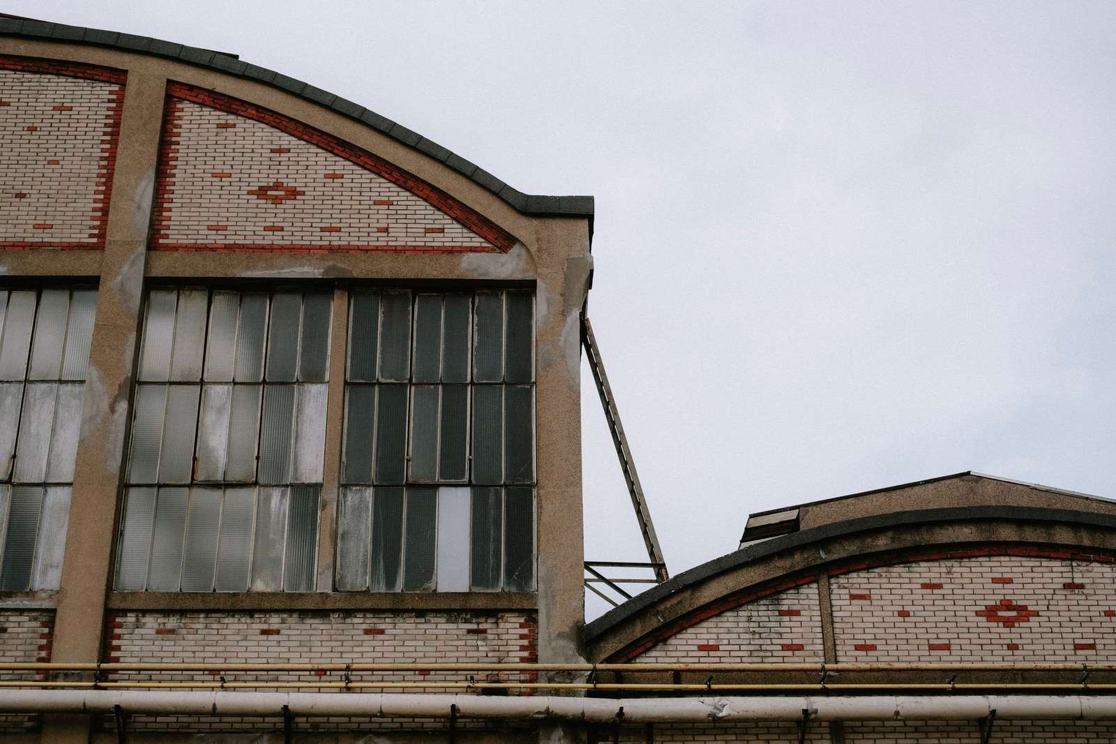 Exterior of a vacant former industrial building with empty windows and overgrown surroundings