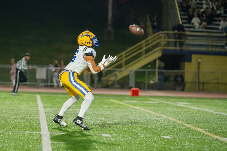 A high school wide receiver catches a football on the field