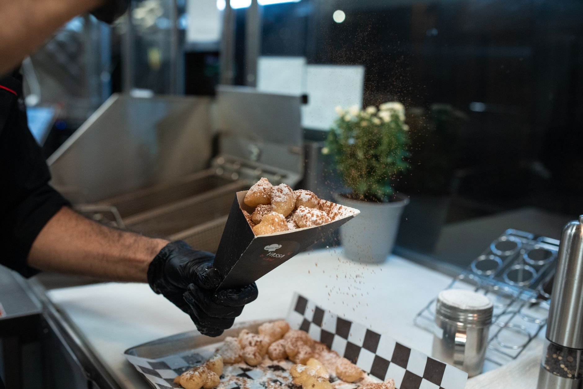 A plate of beignets covered in powdered sugar next to a cup of coffee