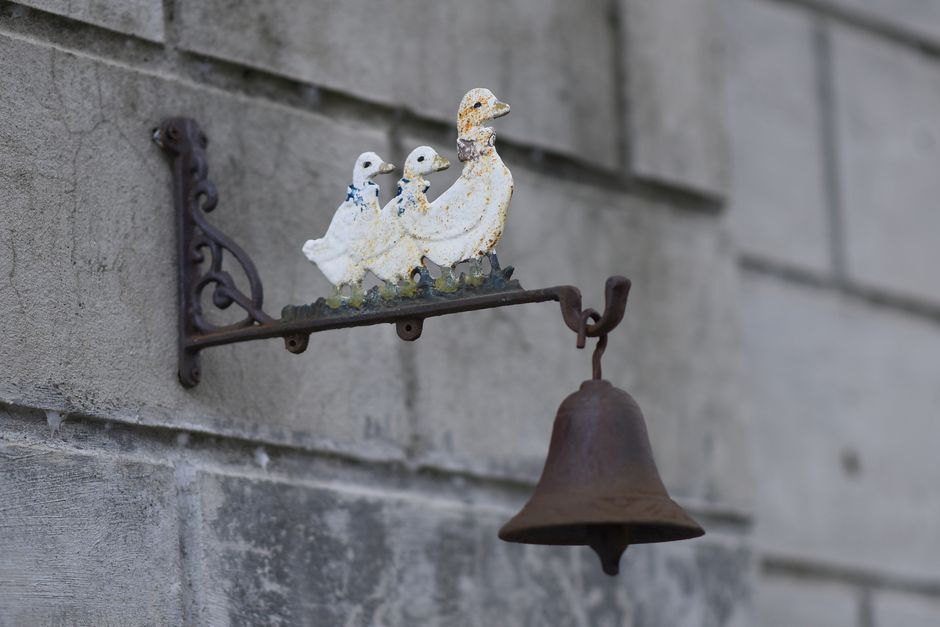 Antique brass bell hanging from an iron yoke on a metal stand