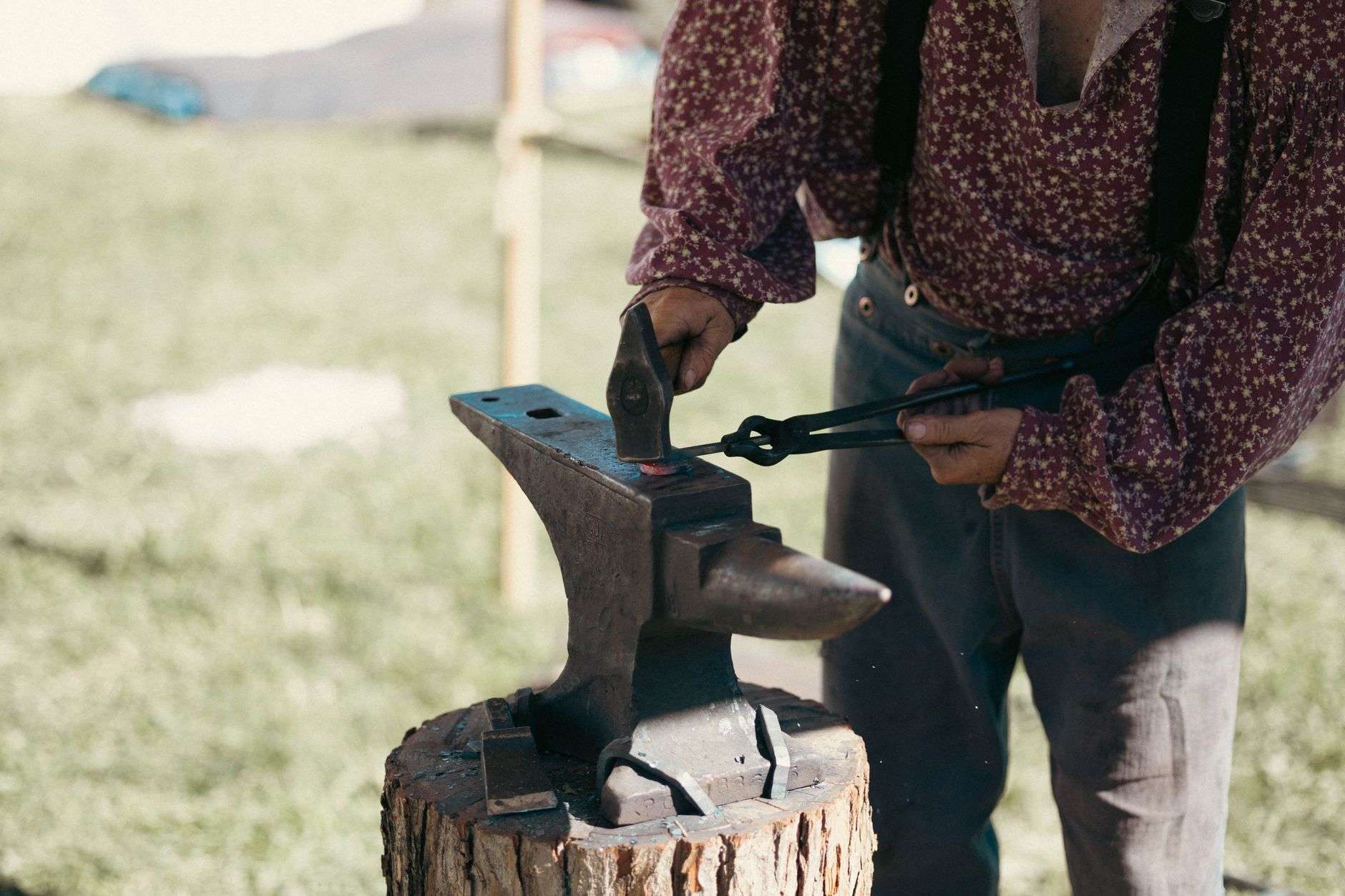 A blacksmith striking glowing orange steel on an anvil with a hammer