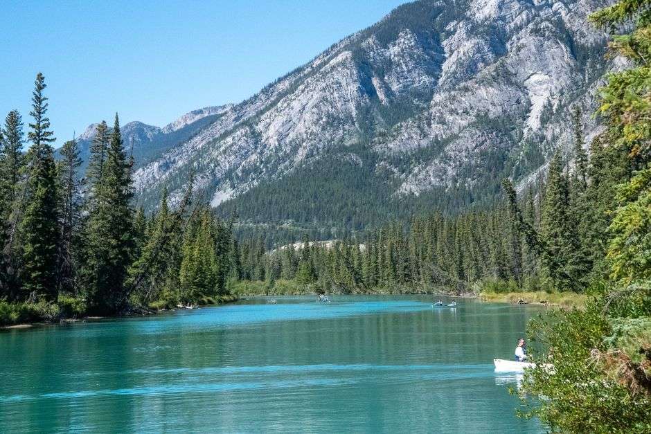 A canoe on a clear shallow river with white sandbars and pine forest
