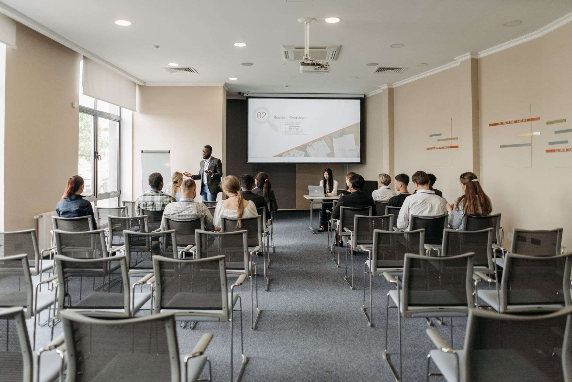 Small group attending a business seminar in a conference room with a presenter and projector screen