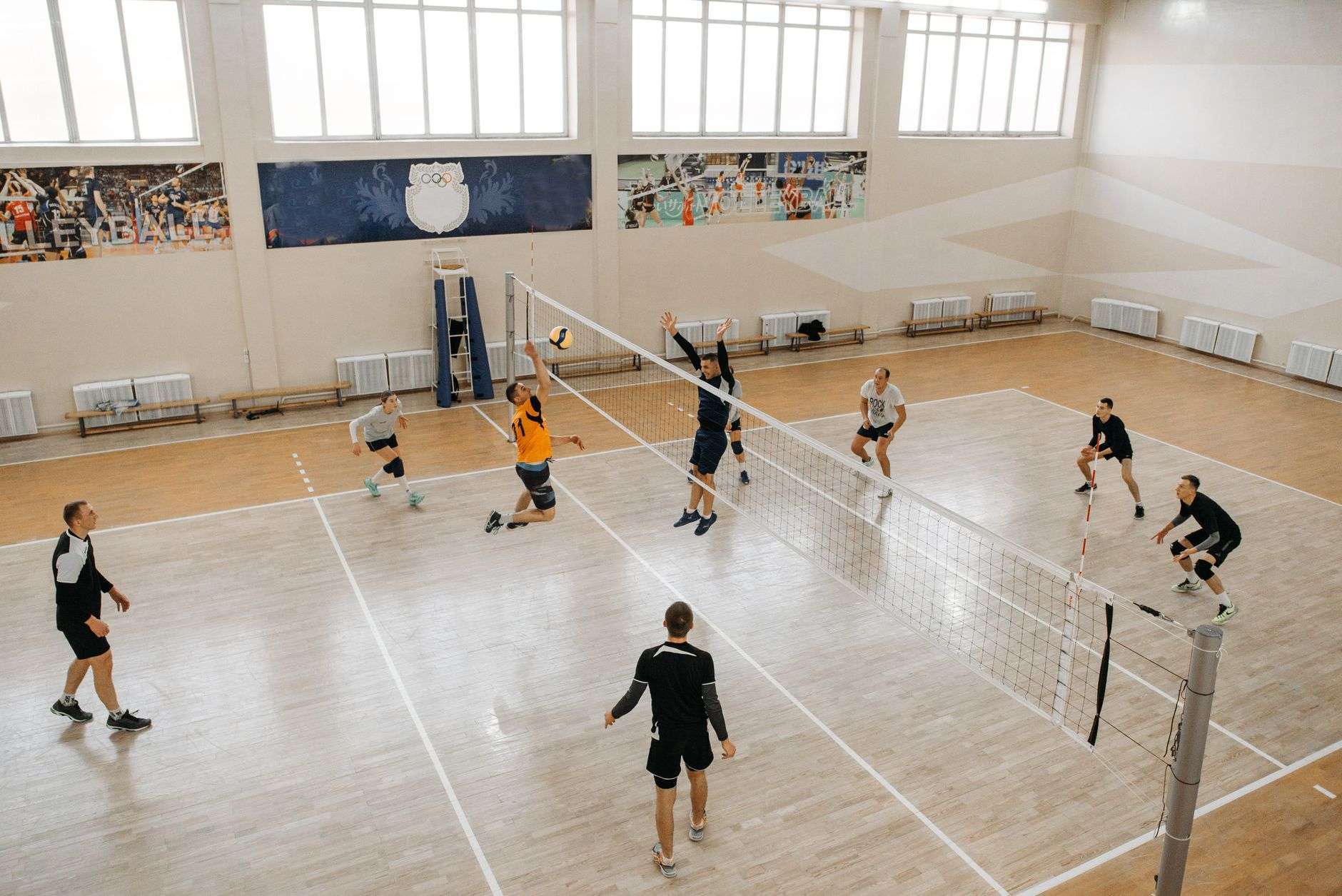 Volleyball players competing at the net on an indoor court