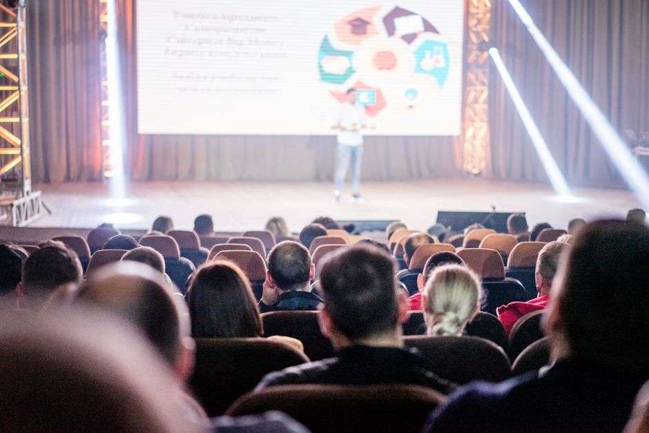 A speaker addressing a business audience from a stage during a workshop