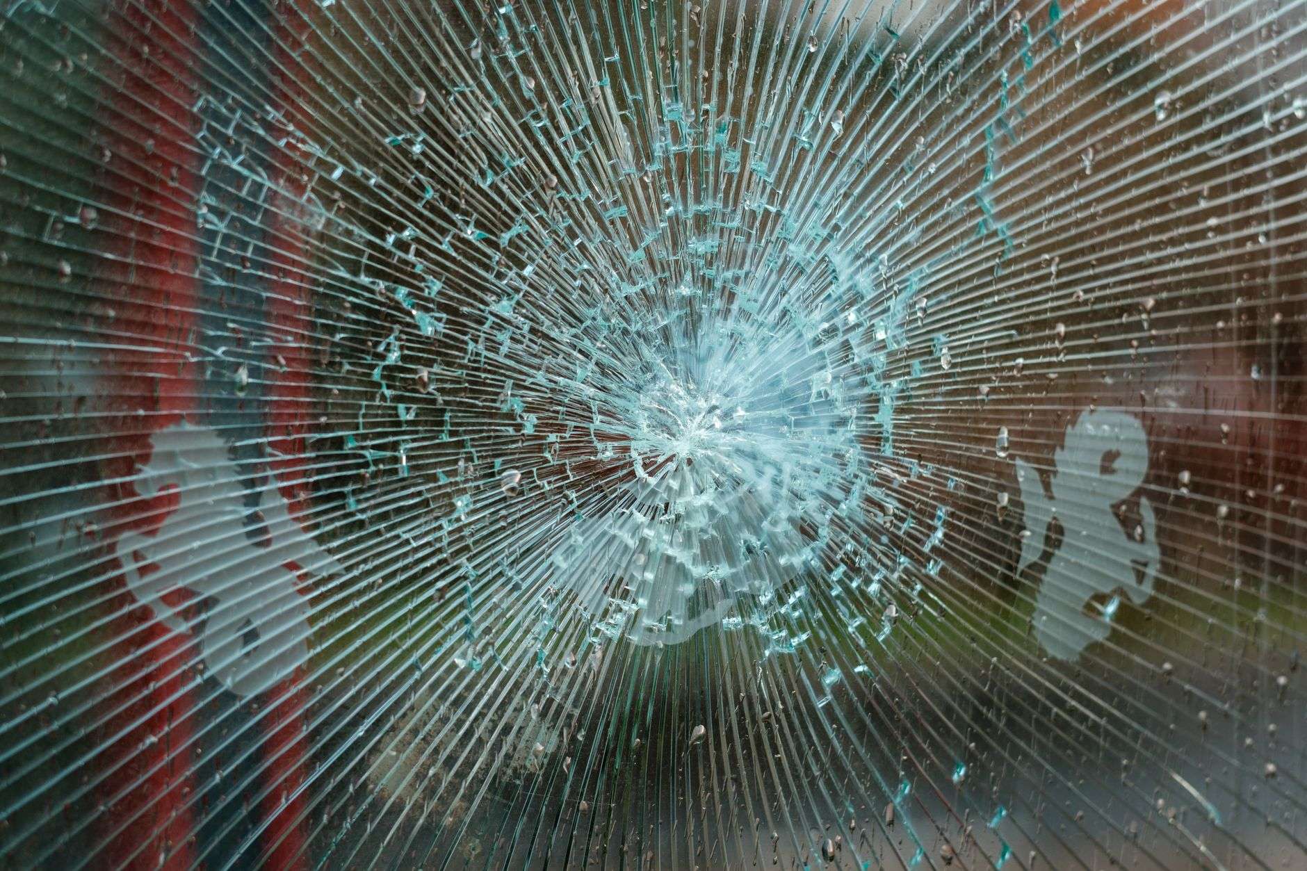 A broken glass storefront on a retail building with shattered panes and damaged framing