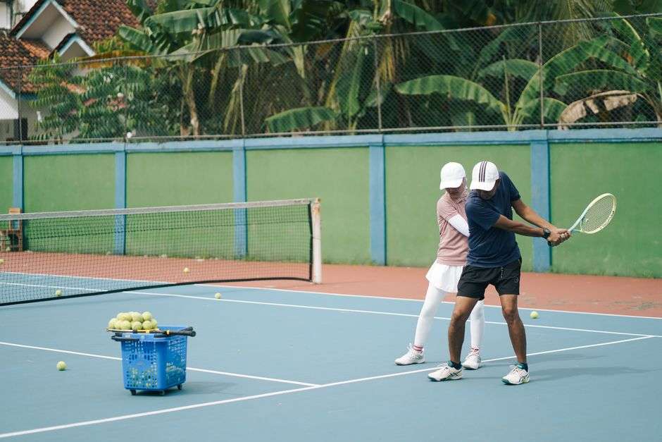Tennis players running drills on an outdoor court during a group fitness class