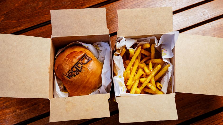 A smash burger with melted cheese and a side of fries on a patio table