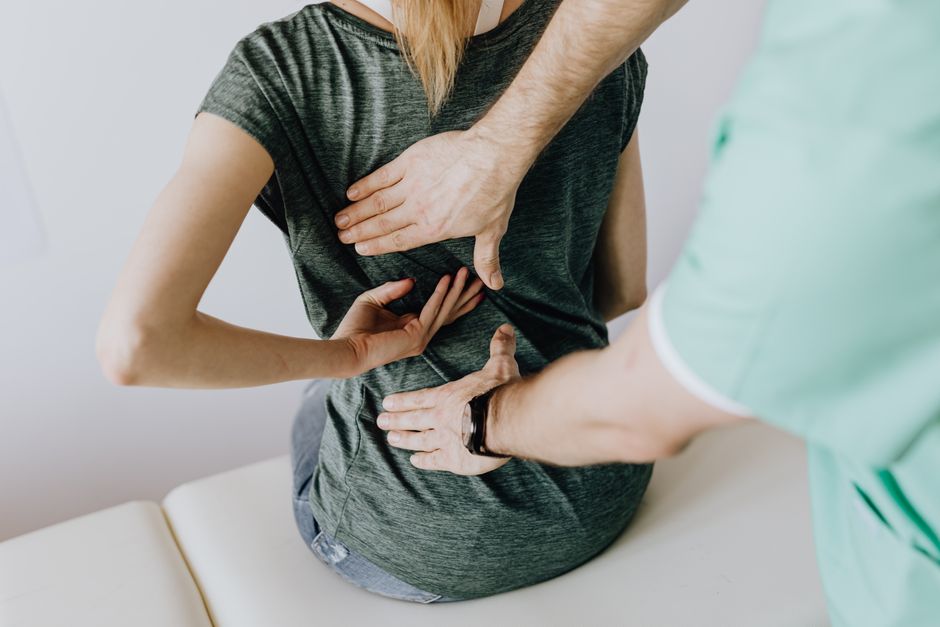 A chiropractor assessing a patient's posture and alignment during an exam