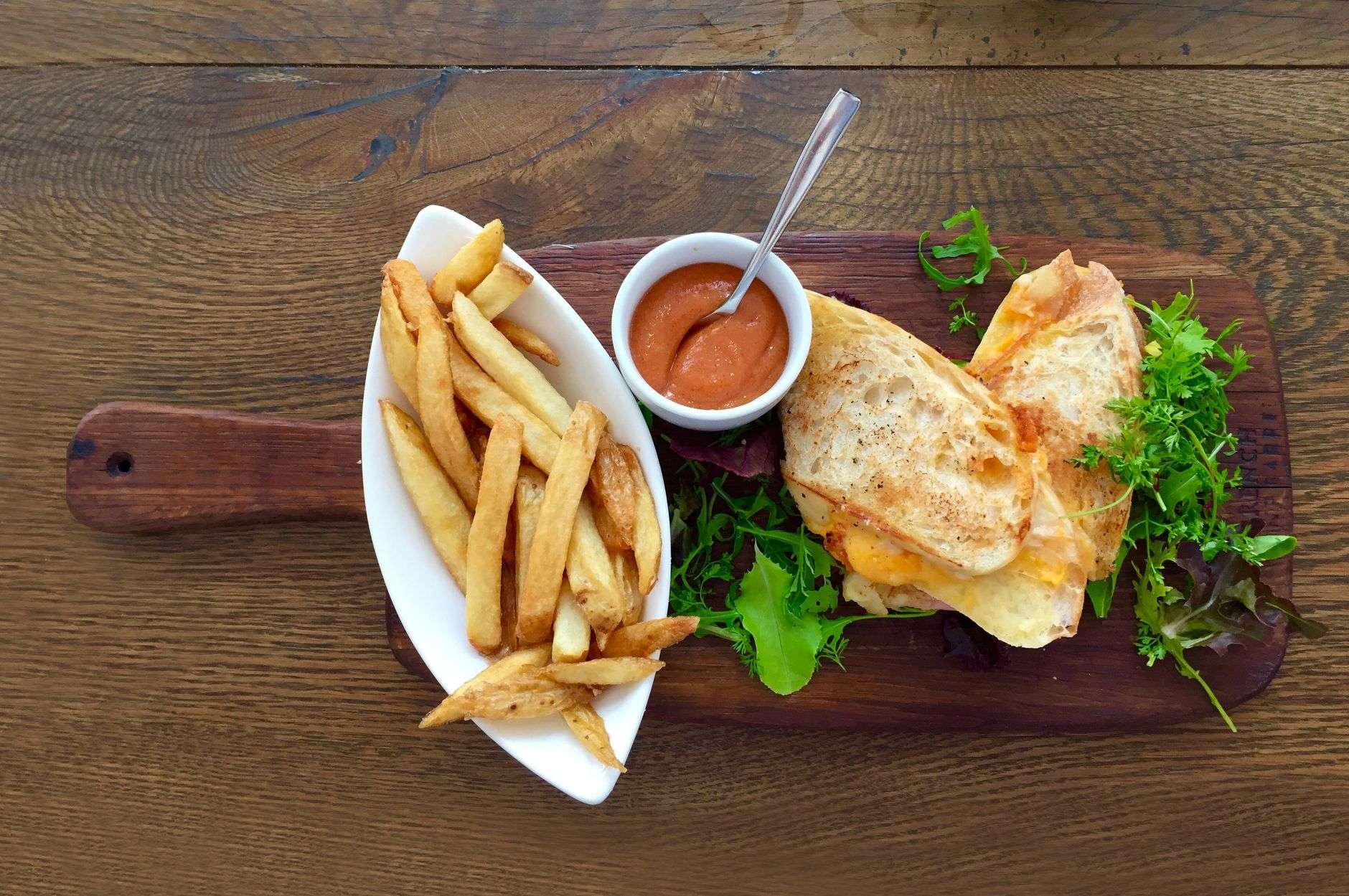 A gourmet grilled cheese sandwich plated on a wooden board