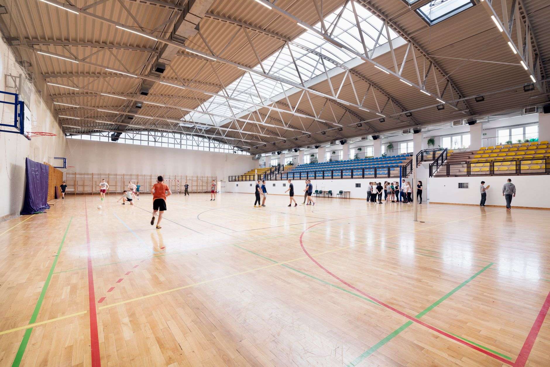 People playing and gathering on an indoor basketball court in a gymnasium