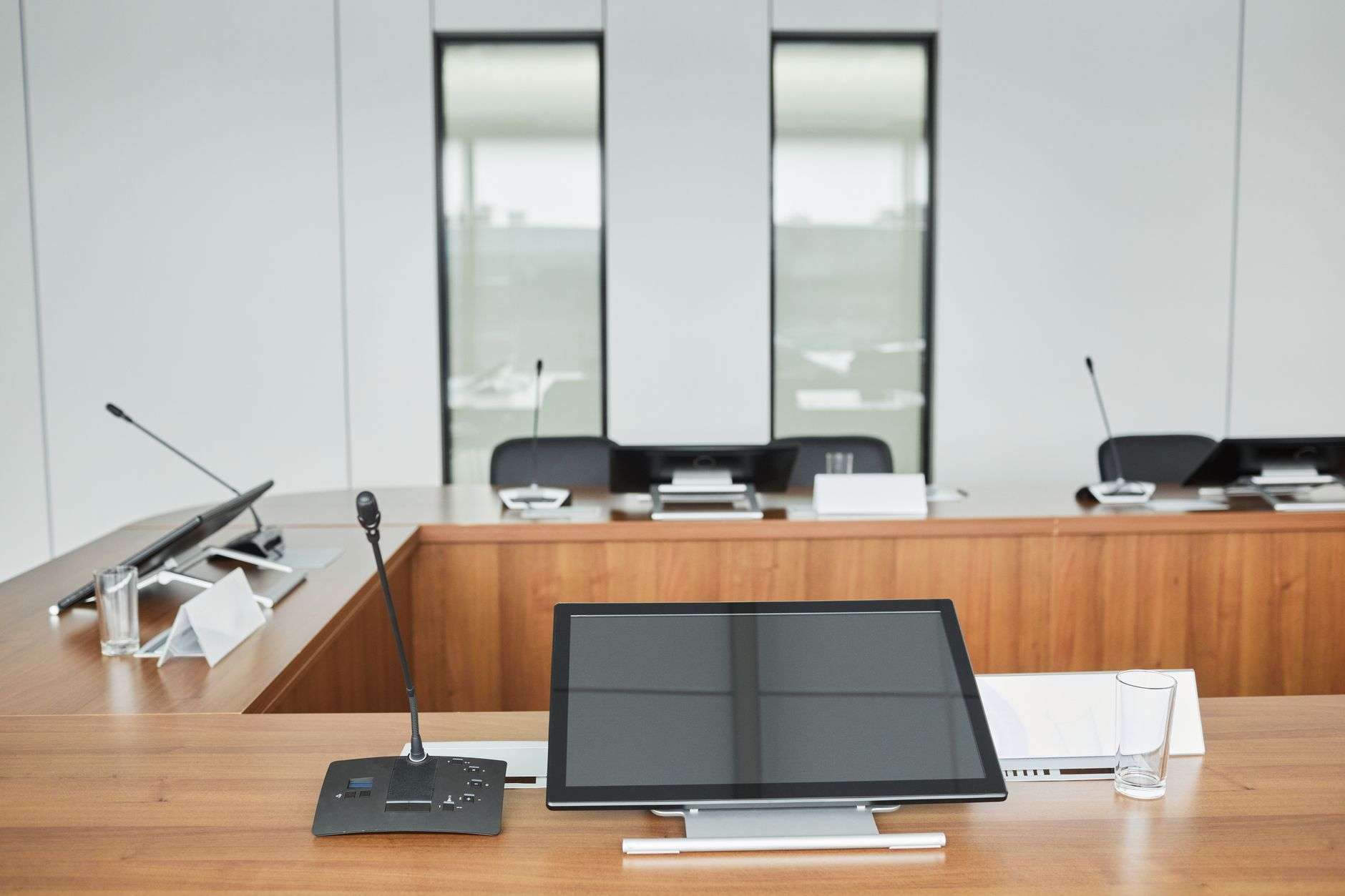 Empty meeting room dais with microphones and video monitors at each seating position