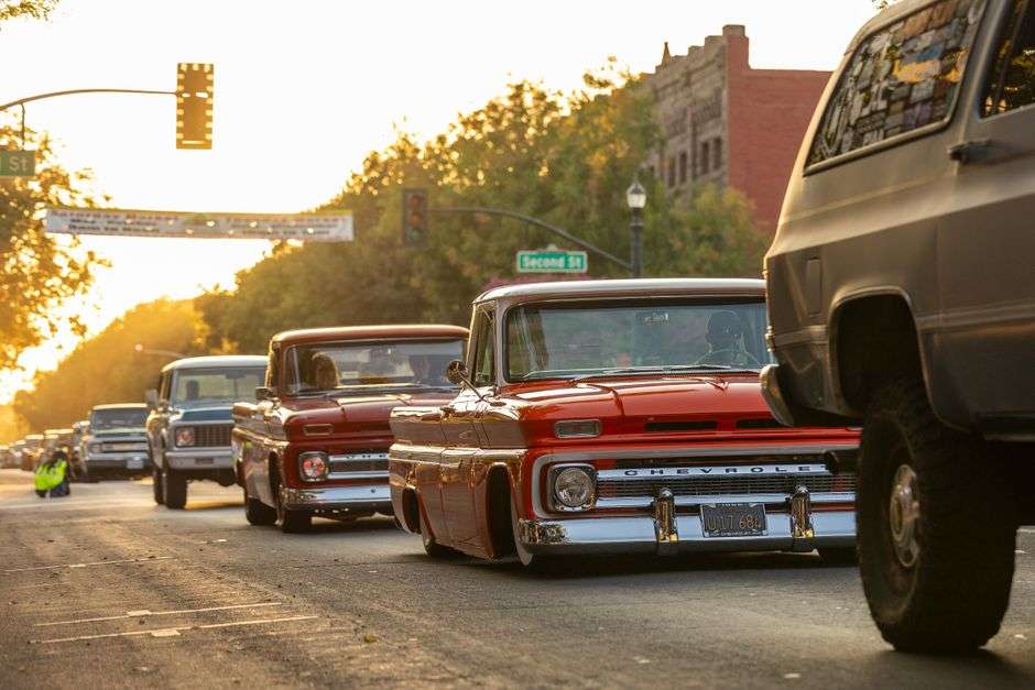 Classic cars lined up along a coastal highway at a car cruise event