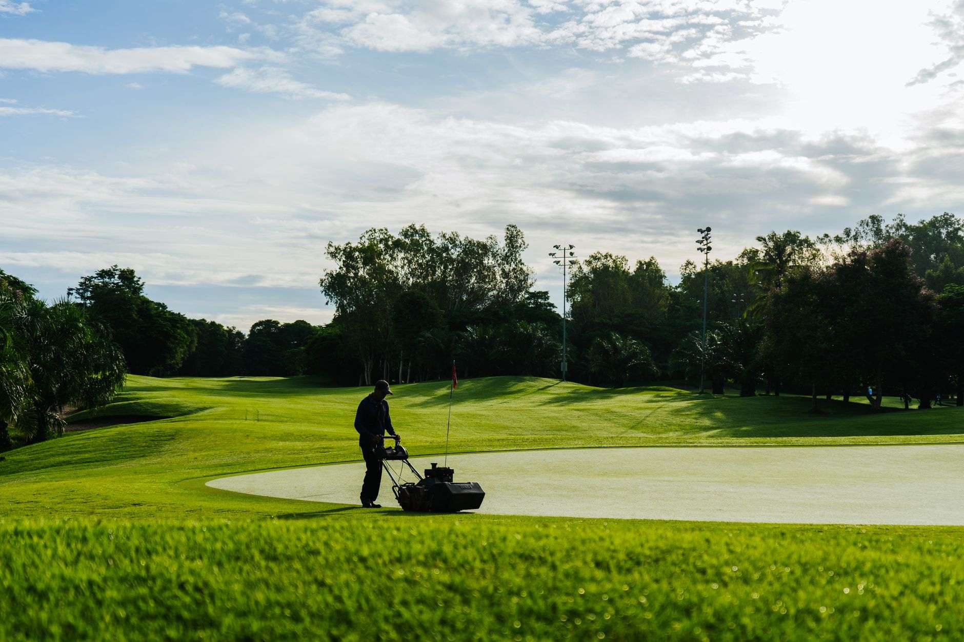 A manicured golf green with a flagstick on a sunny day
