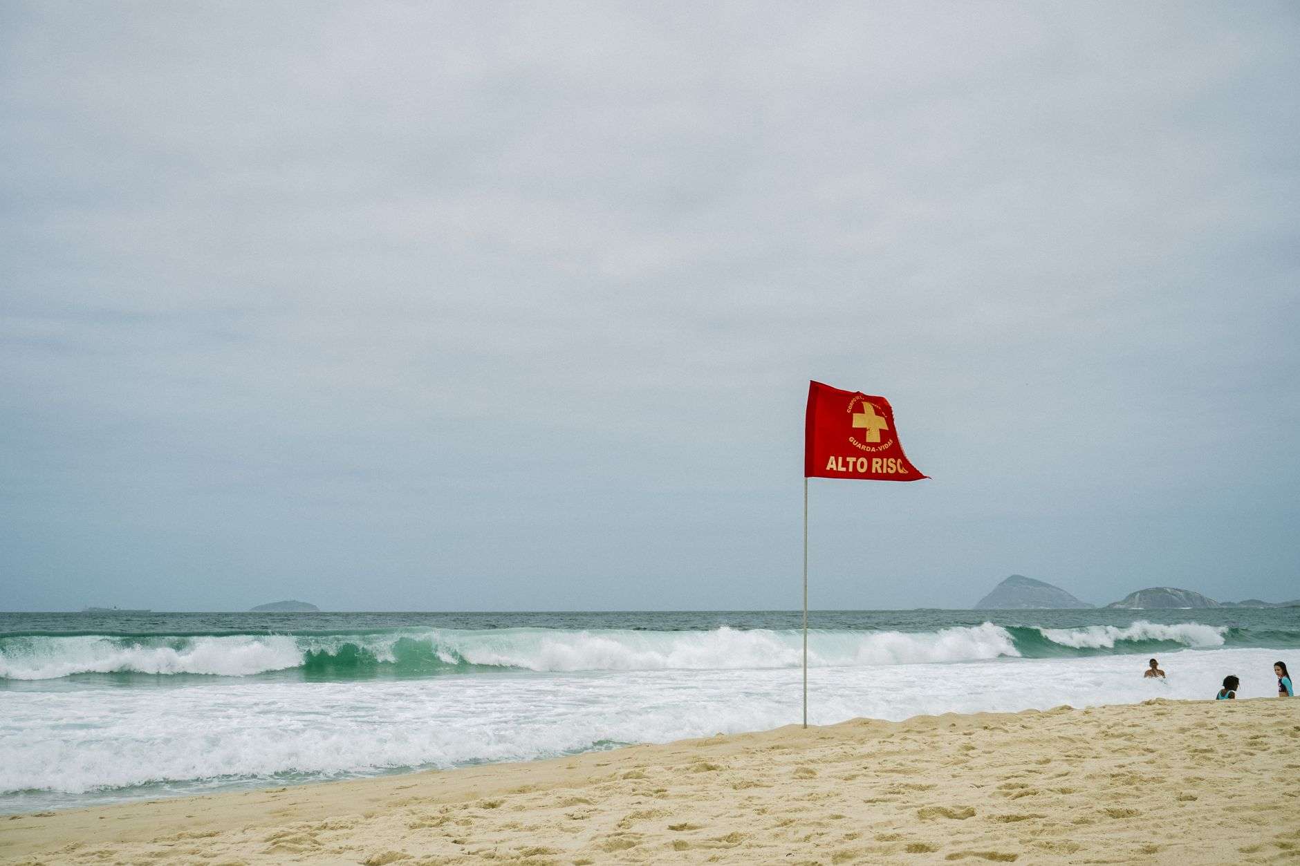 Red warning flag flying on a beach as waves roll onto the shore