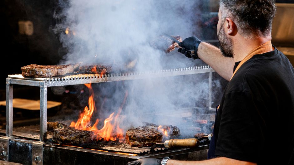 A barbecue restaurant with a smoker and smoke rising from the pit