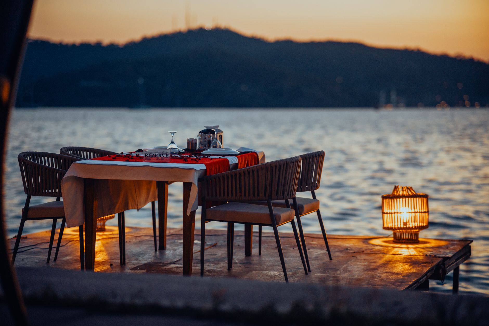 Dinner table set outdoors near the water at sunset