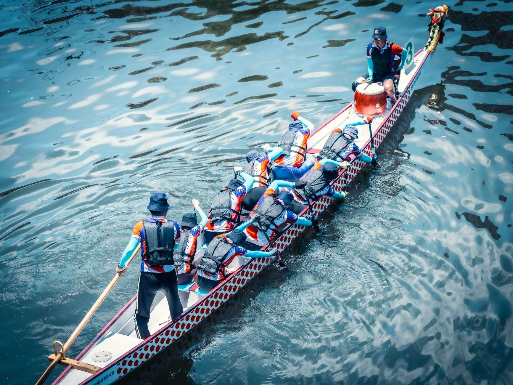 A crew of paddlers in a long dragon boat race across calm water