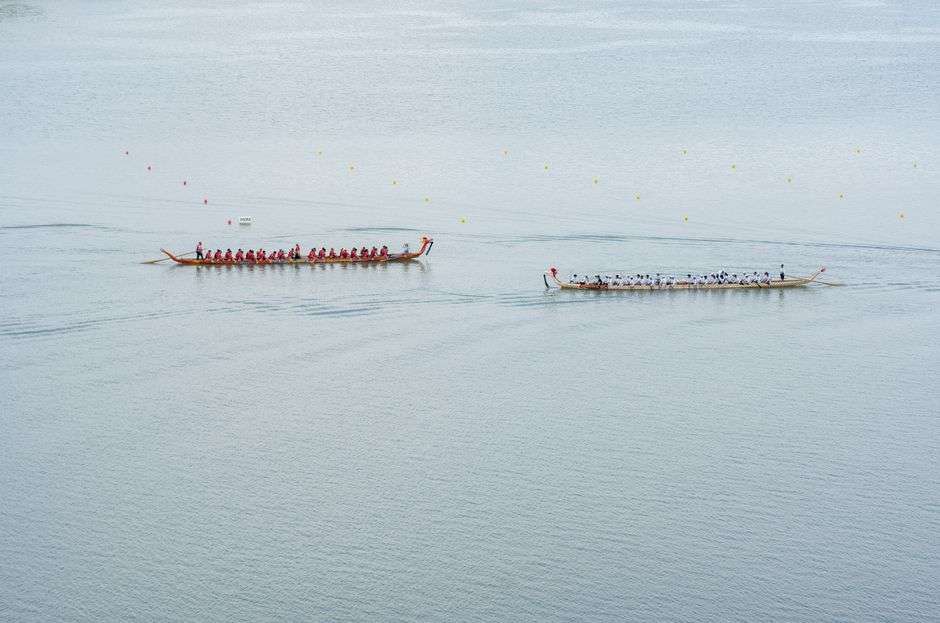 A dragon boat crew paddles in unison during a race on a calm waterway