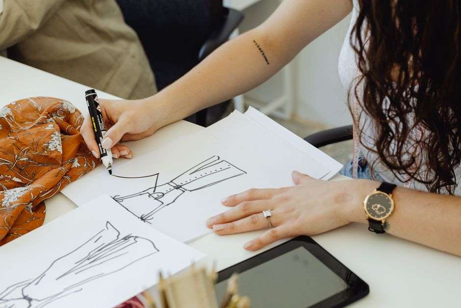 A designer sketching clothing designs at a studio table