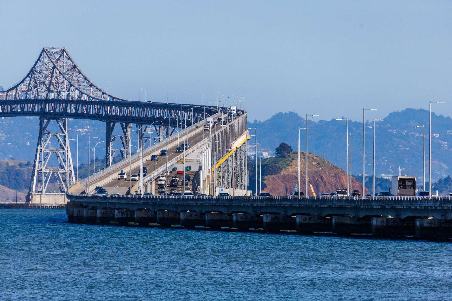 An elevated interstate causeway carrying traffic across a wide coastal bay under a clear sky