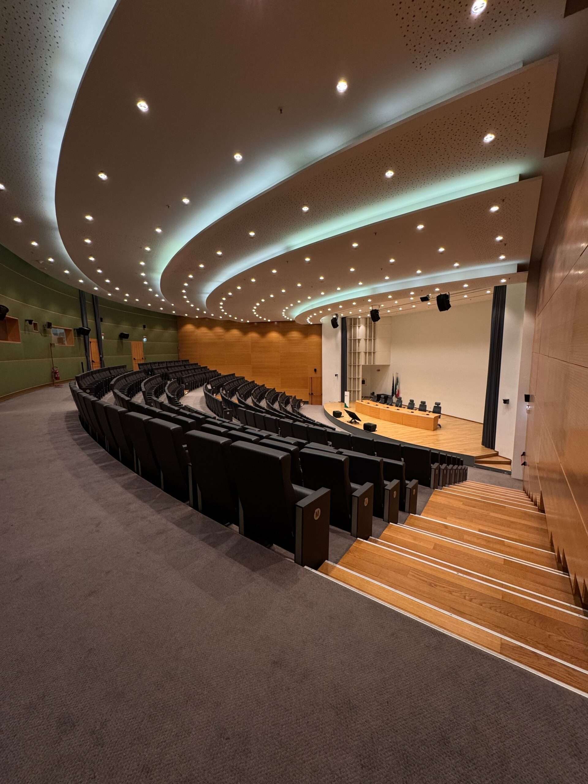 Empty auditorium with rows of seats facing a stage and podium, set up for a public meeting