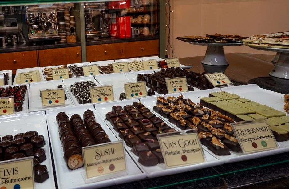 Assorted artisan chocolate truffles displayed in a chocolate shop case