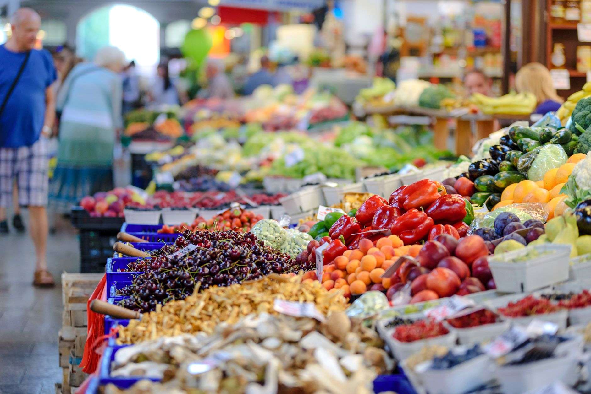 Baskets of fresh vegetables and greens displayed at an outdoor farmers market stand