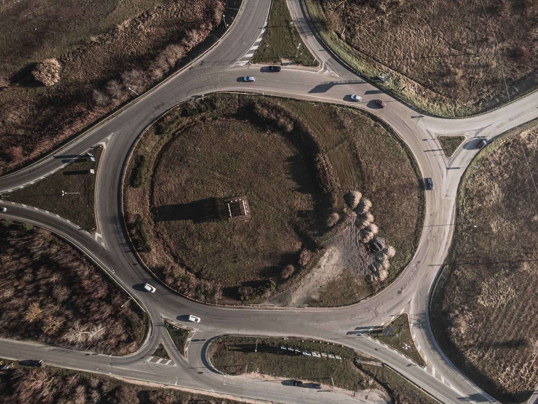 Aerial view of a single-lane roundabout with cars circling at a suburban intersection