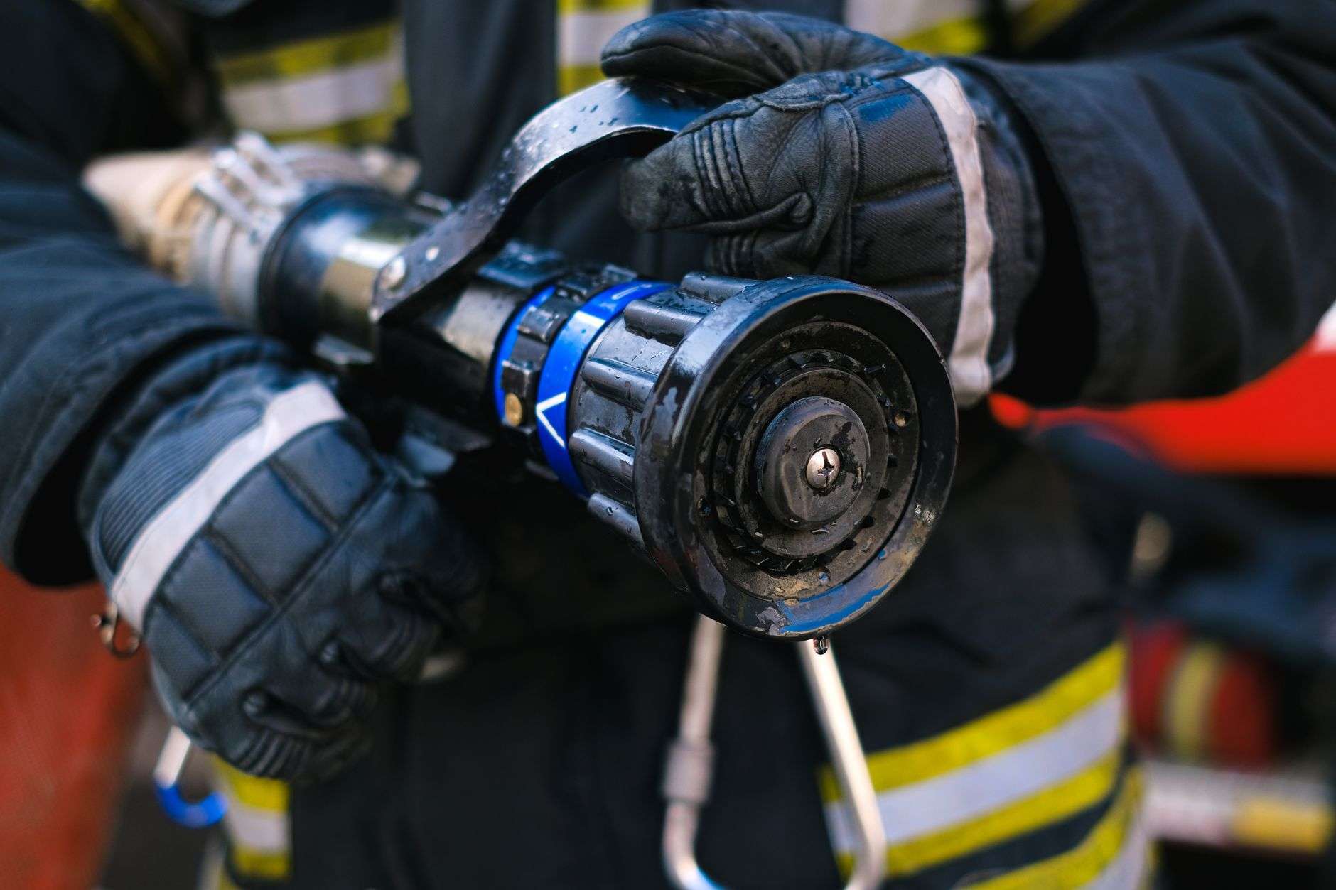 Close-up of a firefighter in protective gear holding a fire hose nozzle