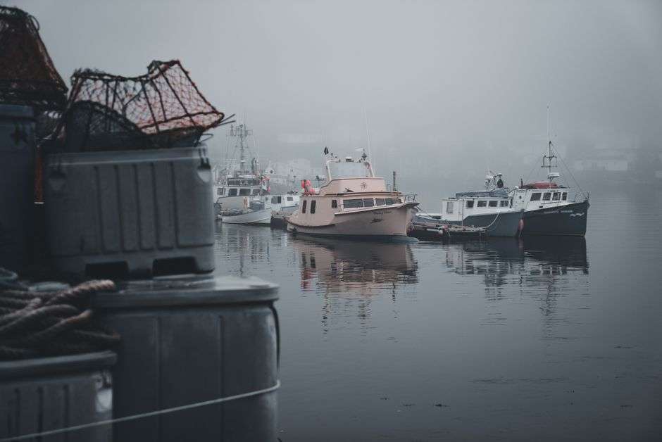 A lobster-style fishing boat with an open stern floating on calm bay water
