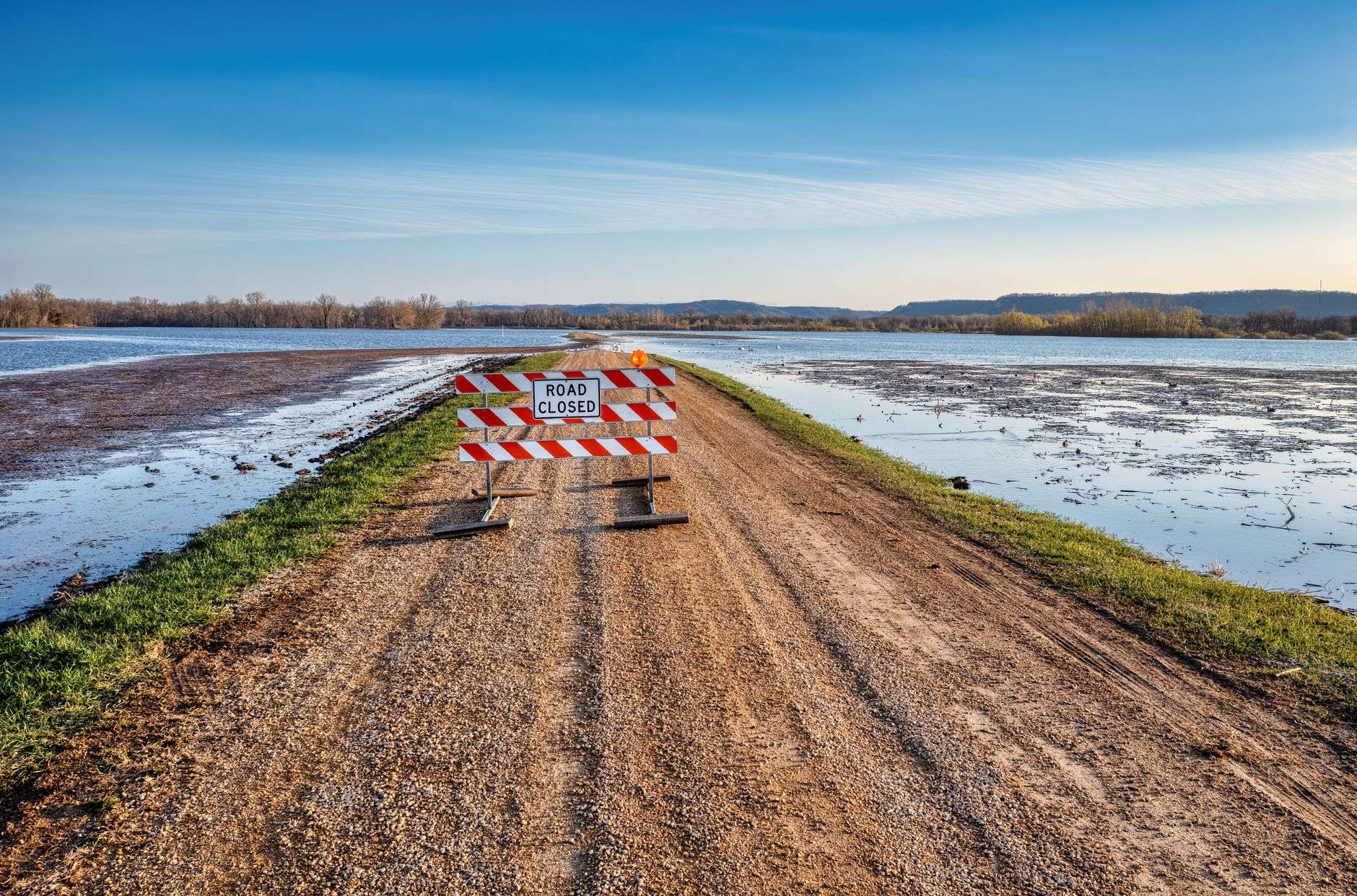Floodwater standing across rural property near a roadway, illustrating drainage-related flooding of private land