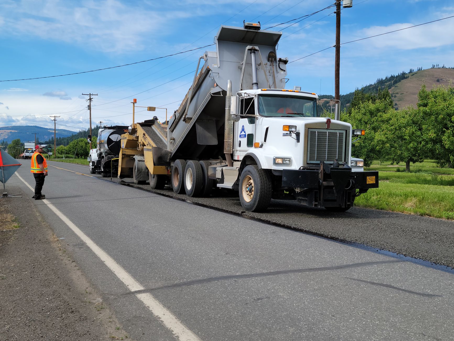 Road crew and paving equipment laying fresh asphalt on a street
