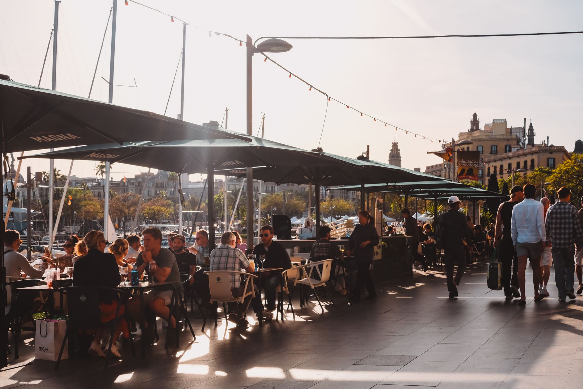 Outdoor restaurant patio overlooking boats docked at a marina at sunset