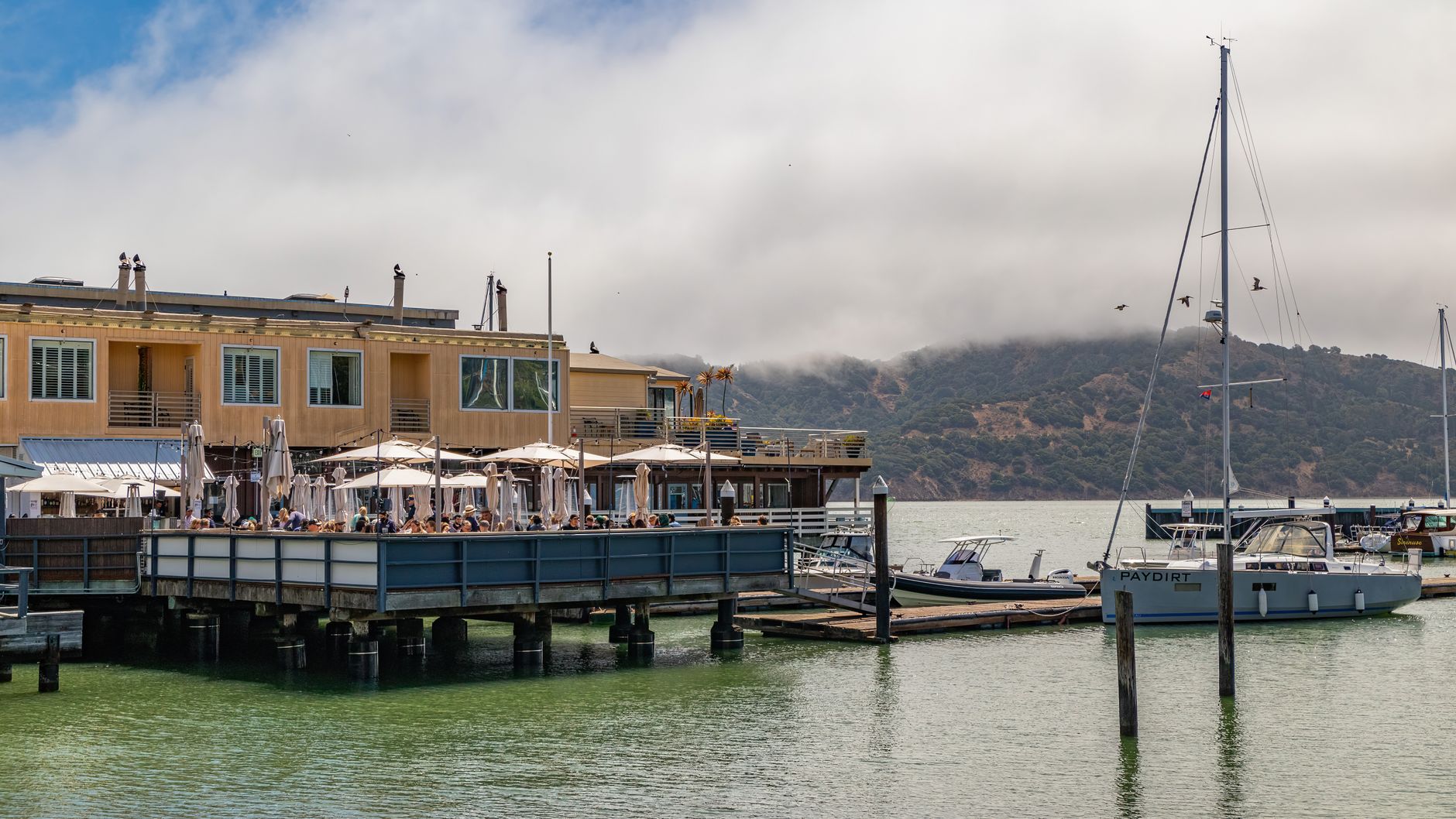 Outdoor deck of a waterfront restaurant overlooking boats on a bayou