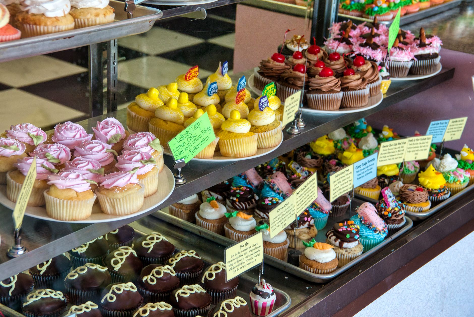 Rows of frosted cupcakes lined up in a glass bakery display case