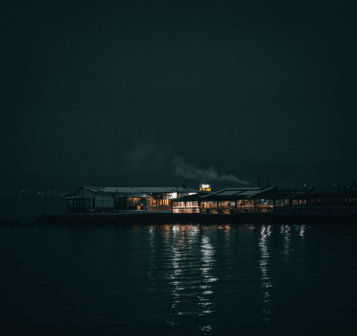 Outdoor restaurant deck overlooking a harbor with boats docked nearby