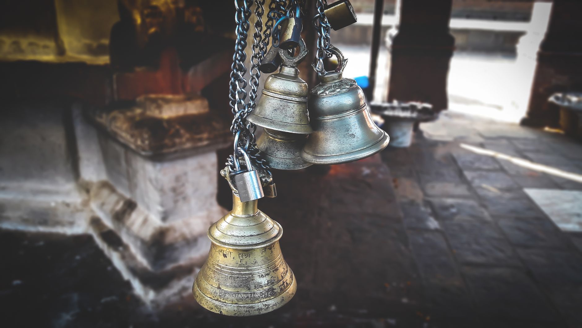 An antique brass bell hanging from a metal yoke