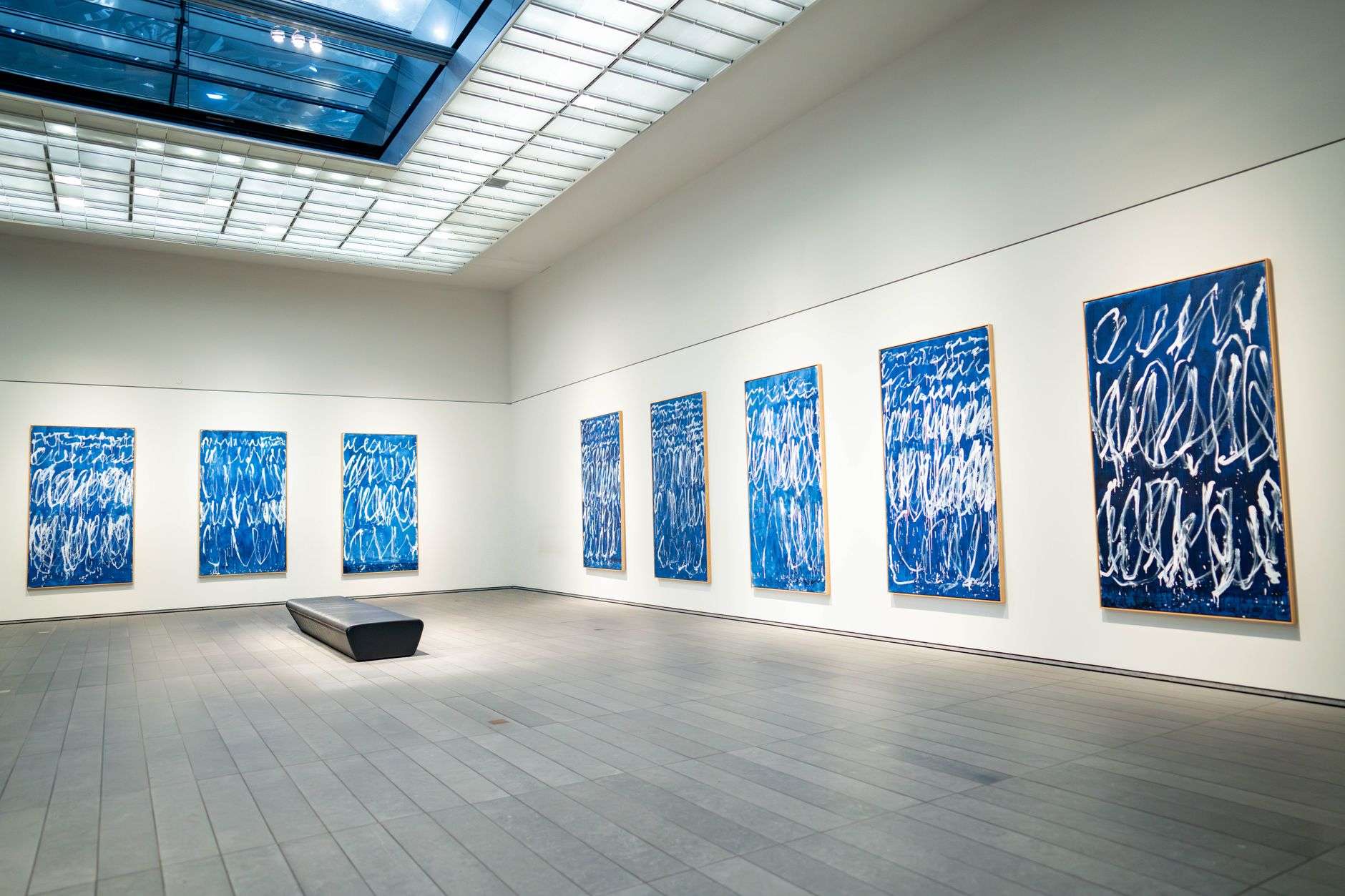 Framed paintings hung on white walls in a bright gallery space
