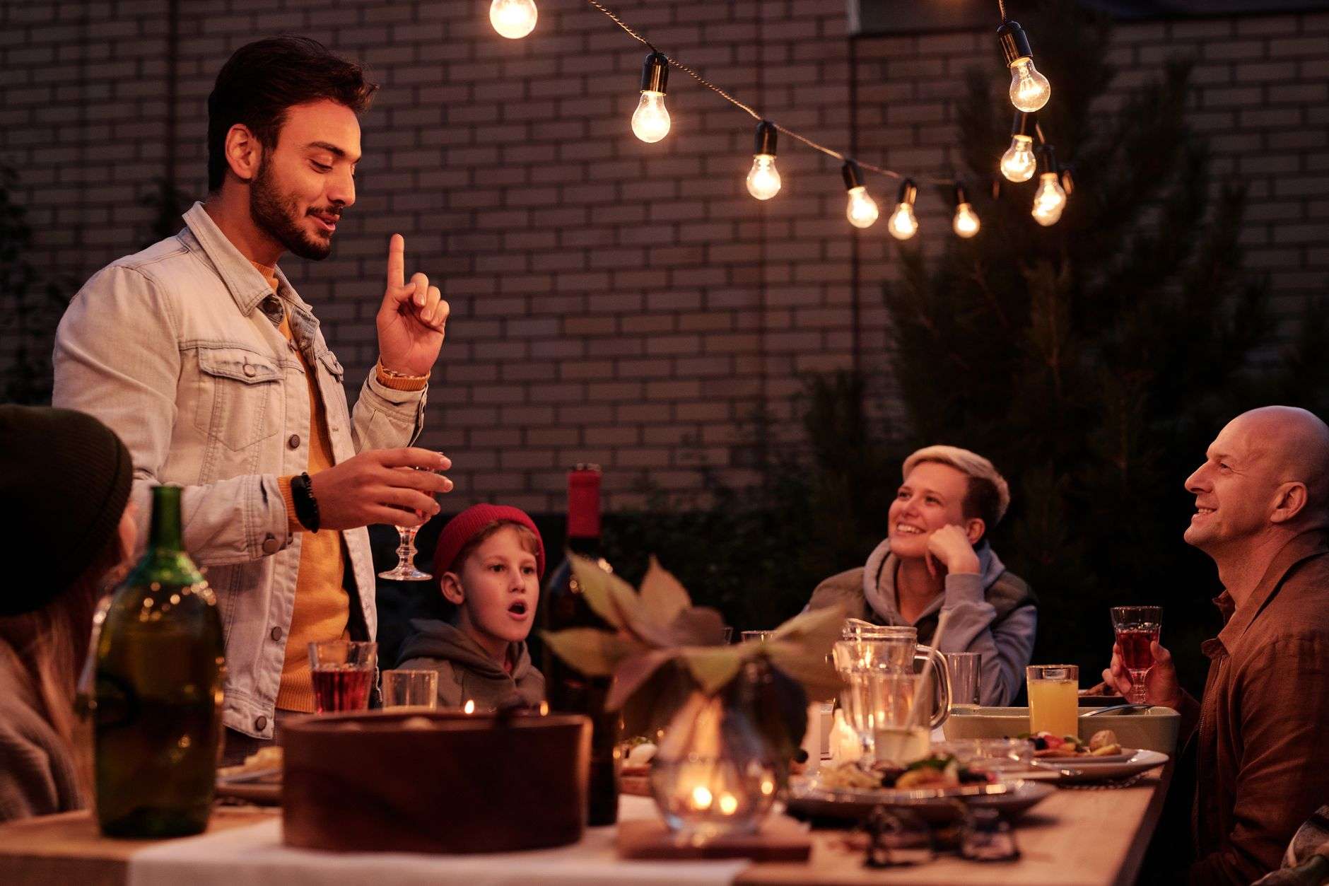 People gathered in an outdoor courtyard with string lights overhead