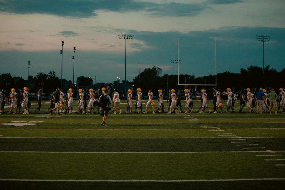 A high school football field lit by stadium lights at night
